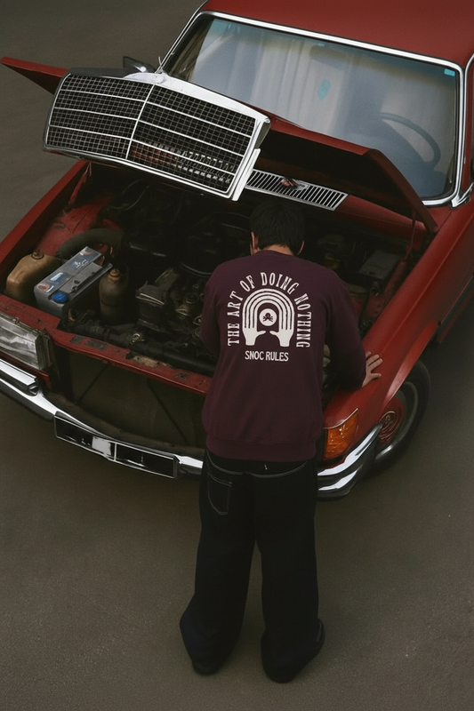 Modelo junto al coche rojo con la sudadera burdeos The Art of Doing Nothing