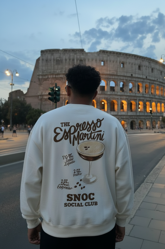 Sudadera Espresso Martini de SNOC vista por la espalda con la receta del cóctel y el sello SNOC Social Club, frente al Coliseo de Roma