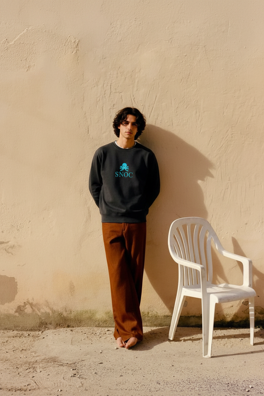 Modelo con la sudadera SNOC pulpo turquesa junto a la pared beige