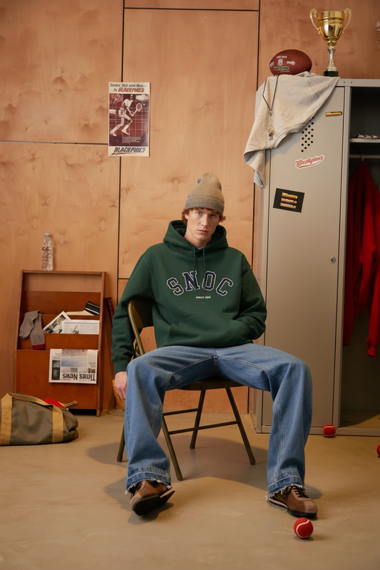 Modelo en el vestuario con la sudadera con capucha verde SNOC Since 1994
