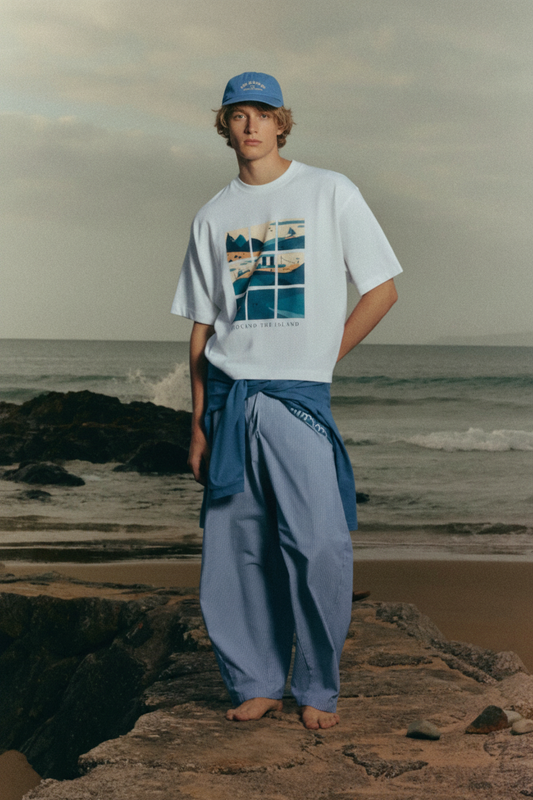 Modelo rubio con la camiseta SNOC Around the Island en las rocas