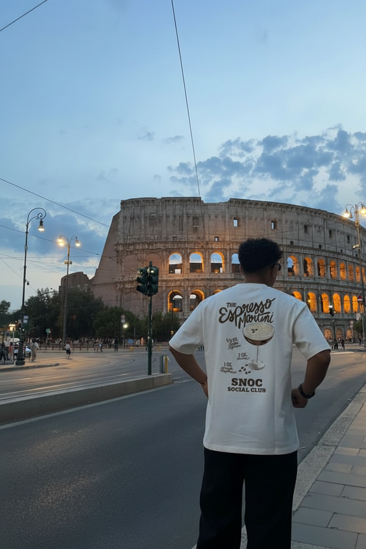 Camiseta Espresso Martini de SNOC vista por la espalda con la receta del cóctel y el sello SNOC Social Club, frente al Coliseo de Roma