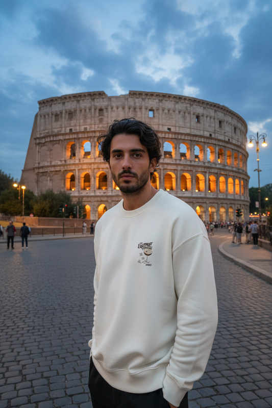 Chico con la sudadera Espresso Martini de SNOC en blanco, vista frontal con la copa estampada en el pecho, frente al Coliseo de Roma